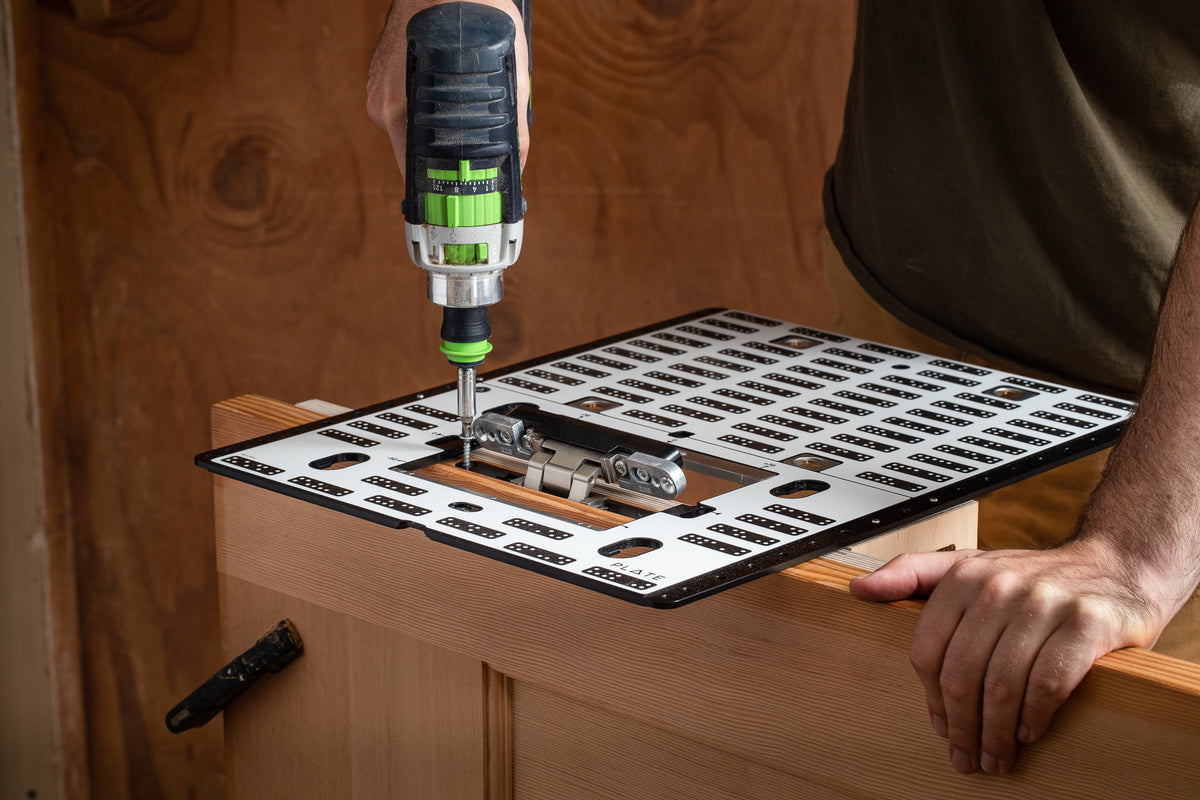 Shaper Tools Plate for Origin Handheld CNC Router in use on a workbench with various woodworking projects