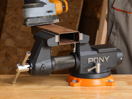 Pony vice holding a piece of metal on a wooden surface with a blurred background